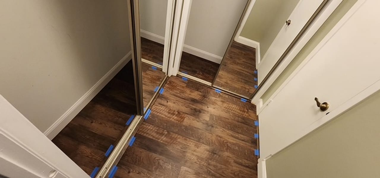 A Frankie D’s install mid-job — new plank floor laid into mirrored closets with expansion spacers still set