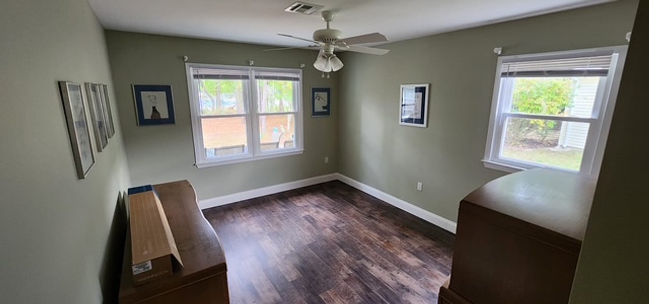 Hand-scraped dark plank flooring in a sage-green bedroom by Frankie D&rsquo;s Flooring